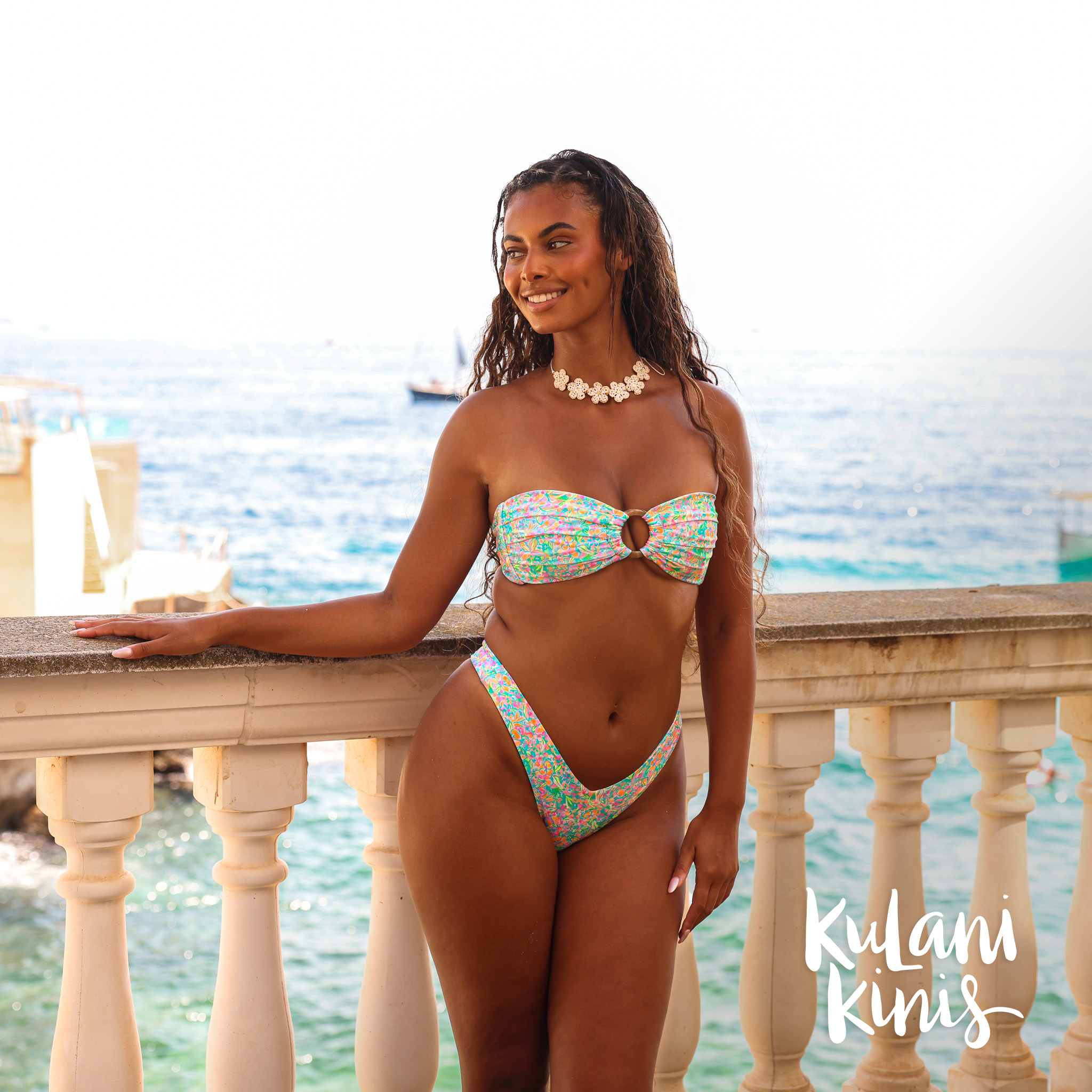 A woman wearing a floral strapless bandeau bikini top from Kulani Kinis – Bikini Village 